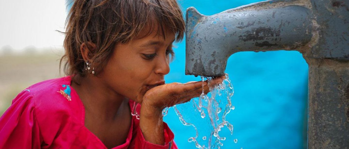 Wasser wirkt - Mädchen trinkt Wasser am Brunnen