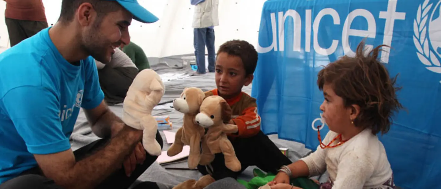 UNICEF-Helfer spielt mit Handpuppen mit Kindern.
