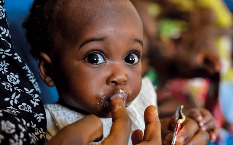 Eine Mutter füttert ihr Baby | © UNICEF/UNI182089/Rich Nigeria: Ein Baby wird mit Erdnusspaste gefüttert
