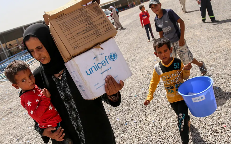Jede Familie erhält ein Versorgungspaket zur ersten Soforthilfe im Flüchtlingslager. | © UNICEF/Khuzaie Irak: Familien tragen Hilfsgüter - Das Versorgungspaket beinhaltet Notfallnahrung, Wasser und Hygieneartikel.
