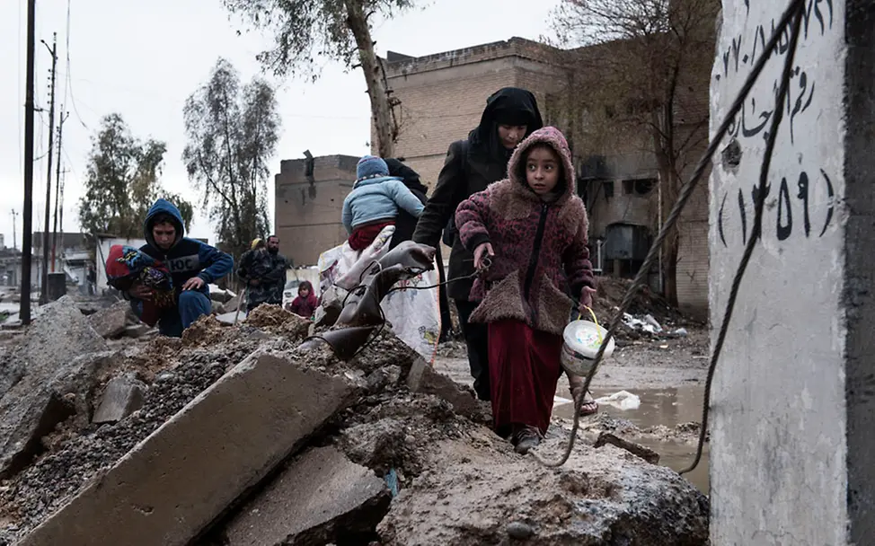 Eine Familie flieht mit ihrem Hab und Gut vor den Kämpfen in Mossul. | © UNICEF/Romenzi Eine Familie flieht durch Trümmer mit ihrem Hab und Gut vor den Kämpfen in Mossul.