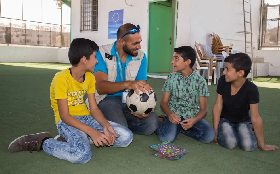 Ein UNICEF-Mitarbeiter spricht mit drei Jungs auf dem Dach des Makani-Zentrums | © UNICEF/Rich Makani: Drei Jungs mit einem UNICEF-Mitarbeiter auf dem Dach eines Makani-Zentrums