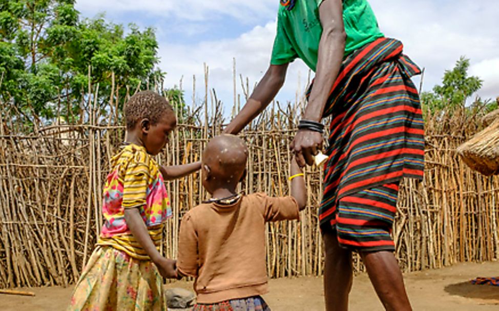 Uganda: Ein Vater tanzt mit seinen beiden Kindern im Freien