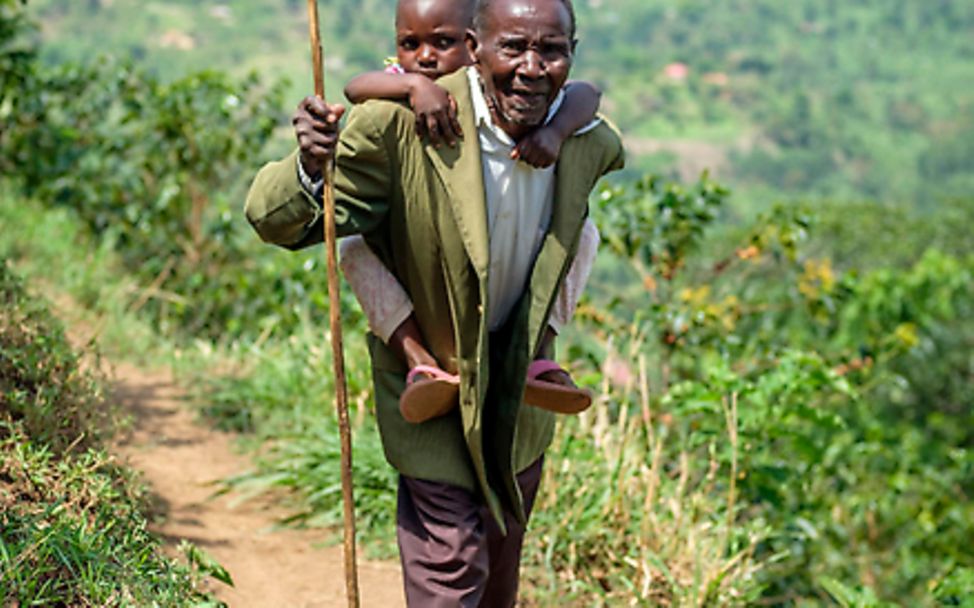 Uganda: Asinet wird von ihrem Großvater auf dem Rücken getragen