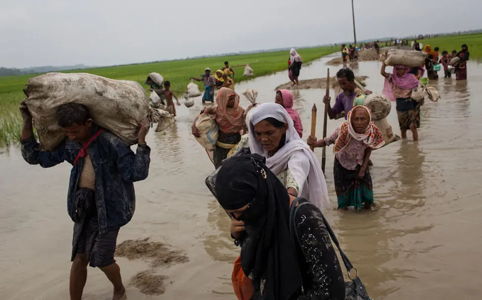 Die Flüchtlinge kämpfen sich durch überflutete Gebiete | © UNICEF/Brown Eine Gruppe Flüchtlinge watet durch Reisfelder und überflutete Landschaften