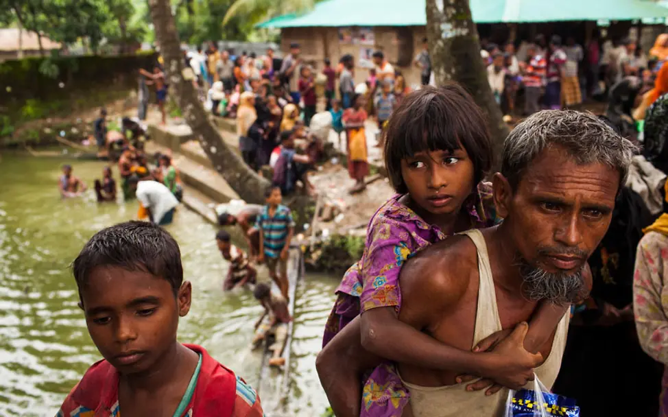 Diese Familie hat die Grenze von Myanmar nach Bangladesch überquert | © UNICEF/Brown Ein Vater trägt seine Tochter nach der Überquerung der Grenze nach Bangladesch