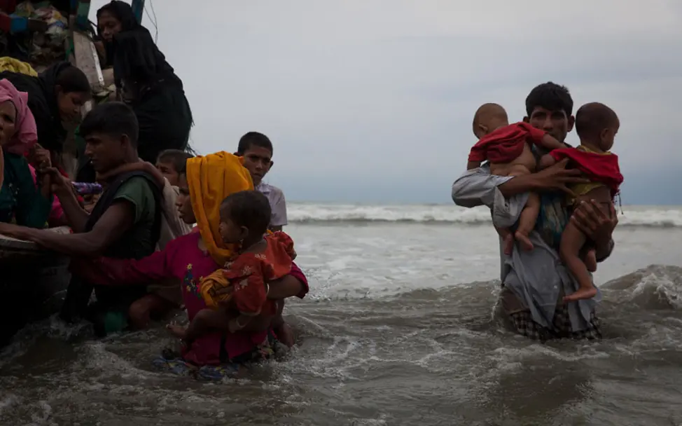 Neue Flüchtlinge treffen nach einer fünfstündigen Überfahrt ein | © UNICEF/Brown Ein Mann trägt zwei Kinder vom Boot durch das Meer