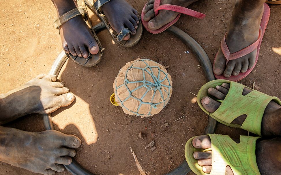 Uganda: Kinder stehen um einen Fußball der aus Lumpen gemacht wurde