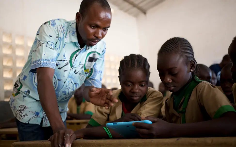Ein Lehrer erklärt Schülern in Kamerun etwas an einem Tablet. | © UNICEF/Prinsloo Ein Lehrer erklärt Schülern in Kamerun etwas an einem Tablet.