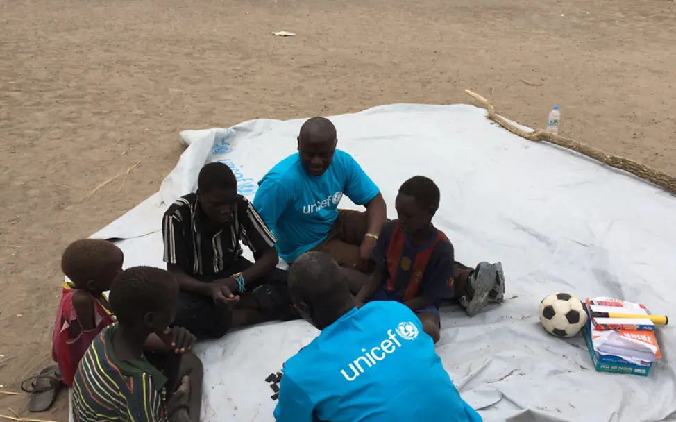 Das Spielen hilft den Kindern um sich besser zu entwickeln | © UNICEF/Michael Charley Südsudan: Michael spielt mit Kinder auf einer Plane um sie von schlimmen Erinnerungen abzulenken
