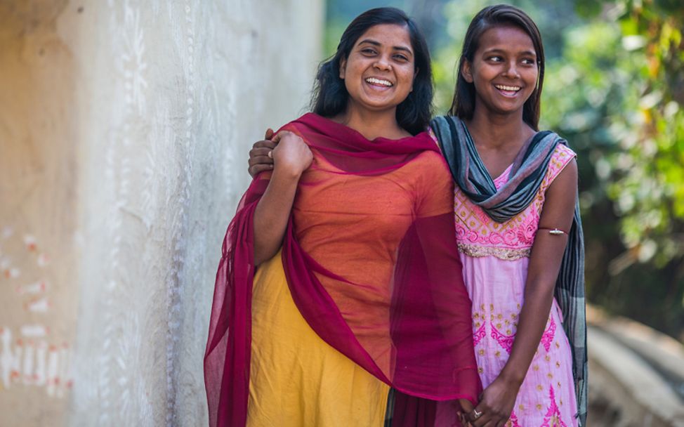 Indien: Zwei Mädchen lachen fröhlich außerhalb ihres Dorfes