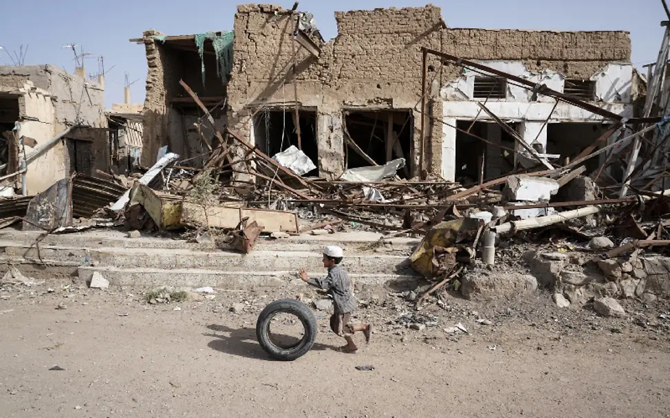 Trotz all der Zerstörung findet dieser Junge ein Spielzeug | © UNICEF/Clarke for UNOCHA Jemen: Ein Junge spielt vor einem zerstörtem Gebäude
