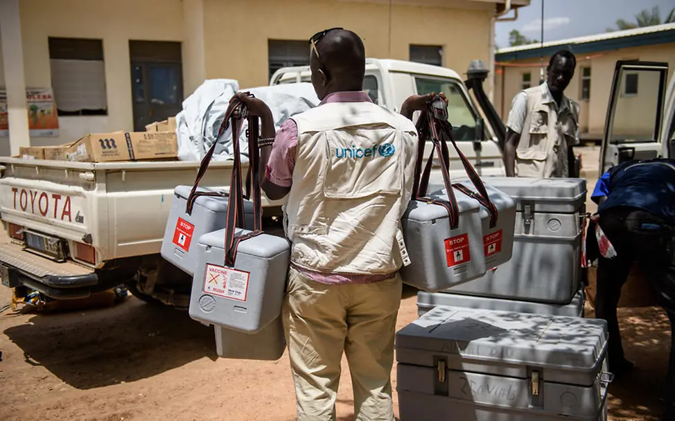 UNICEF-Helfer trägt Kühlboxen | © UNICEF Hilfsgüter im Südsudan: UNICEF-Helfer trägt Kühlboxen