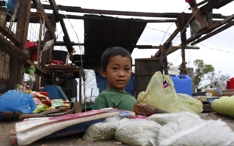 Ein Junge zwischen den Dingen, die von seinem Zuhause nach dem Taifun noch übrig sind | © UNICEF/Maitem Philippinen Taifun Mangkhut: Ein Junge in seinem zerstörten Zuhause