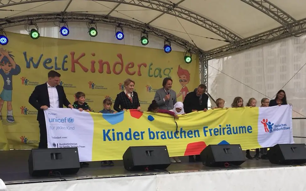 Weltkindertag: Bühnenprogramm am Weltkindertag in Berlin. Es wird ein großes Banner gehalten. 