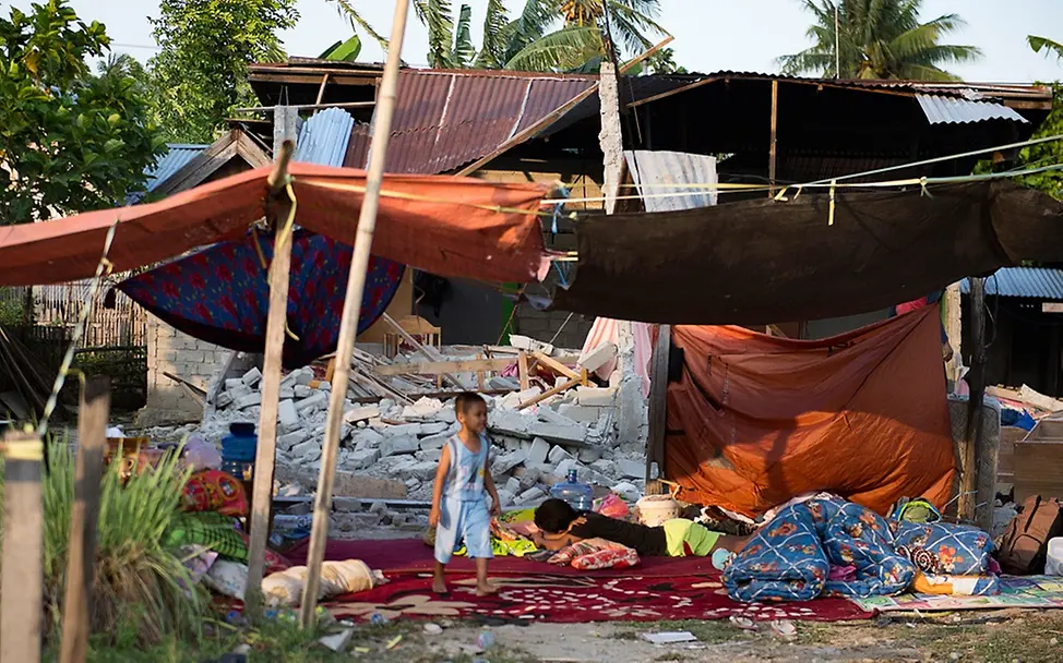 Jungen vor den Trümmern eines Hauses in Palu. | © AFP PHOTO/Bay ISMOYO Junge vor den Trümmern eines Hauses in Indonesien