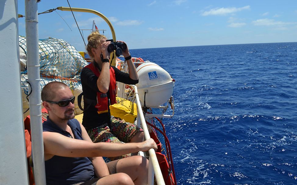 Carlotta mit Fernglas auf einem Rettungsschiff.