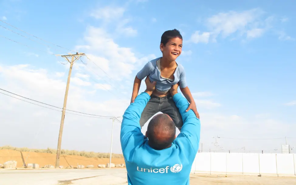 Jordanien: Ein UNICEF-Helfer hebt einen Jungen hoch