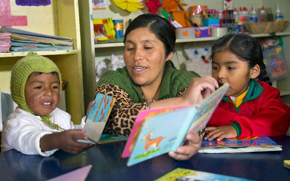 Eine Erzieherin liest Kindern in indigener Sprache vor. 