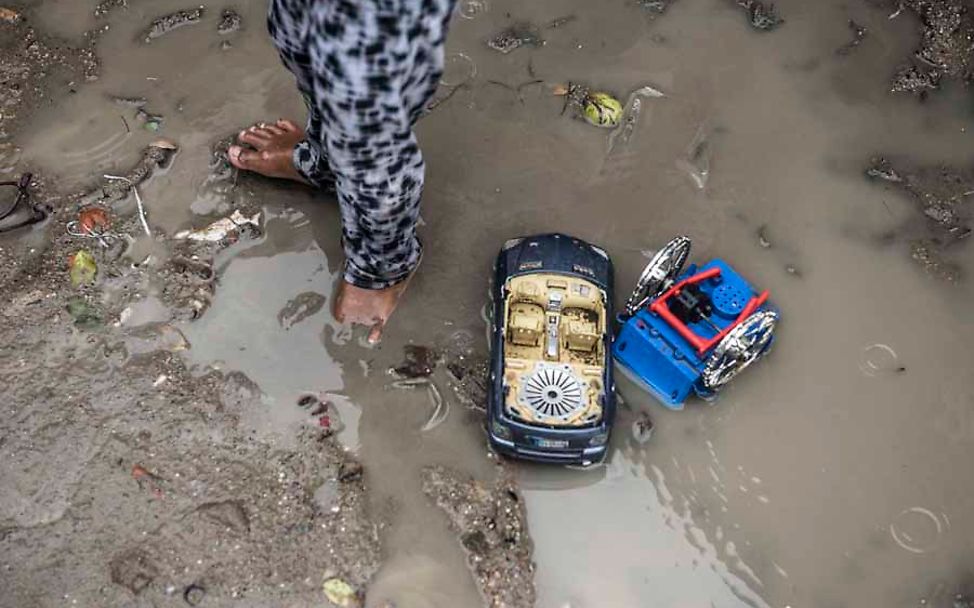 Cambodia: Ein Junge steht barfuß in einer Schlammpfütze vor seinem Zuhause.