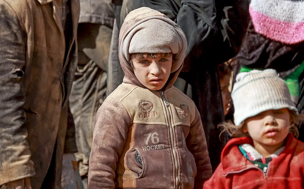 Syrien Anfang des Jahres: Die Gewalt der Kämpfe zwingt viele Kinder und ihre Familien zur Flucht. | © UNICEF/Souleiman Zwei Kinder mit verstaubten Gesichtern in einer Gruppe von Flüchtlingen.