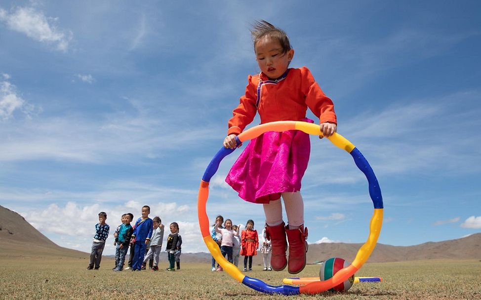 Mongolei: EIn Mädchen spielt mit einem Reifen