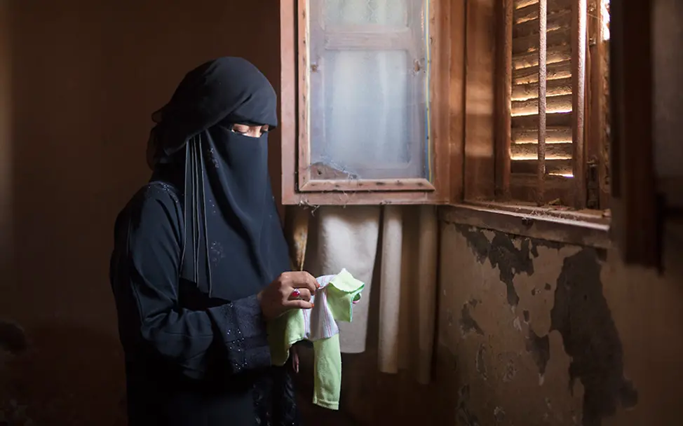 Yasmin trauert um ihre verstorbenen Kinder. | © UNICEF Jemen: Yasmin hält die Kleidung ihres verstorbenen Kindes in den Händen.