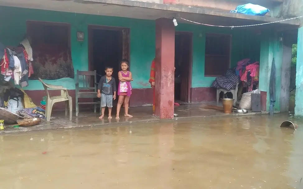 Zwei Kinder vor der Überflutung, die starke Regenfälle in den letzten Wochen hervorgerufen haben. | © UNICEF Nepal/Rajesh Jha Nepal: Zwei Kinder stehen vor dem überfluteten Vorhof ihres Hauses.