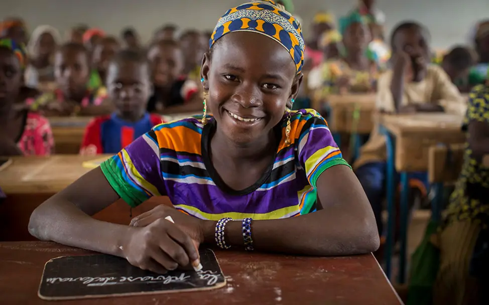 Fatoumata darf endlich zur Schule gehen. | © UNICEF/Dicko Mali: Die 12-Jährige Fatoumata schreibt mit Kreide auf eine Schiefertafel.
