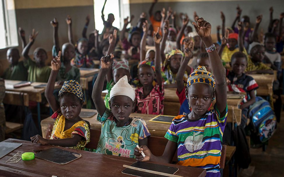 Mali: Fatoumata und ihre Mitschüler sitzen zu dritt in einer Reihe und melden sich.