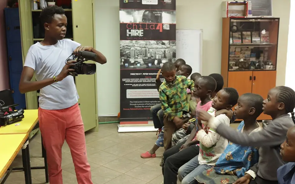Patrick zeigt jüngeren Kindern die Film- und Fotokunst. | © Dagoretti Film School Kenia: Patrick zeigt jüngeren Kindern die Kameraarbeit im Film- und Fotokurs.