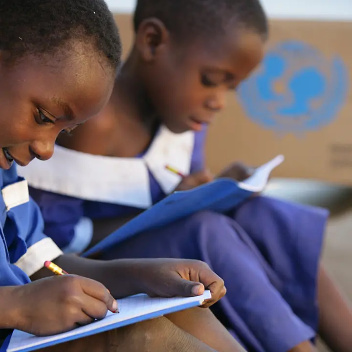 Kinder können mit Ihrer Hilfe zur Schule gehen. | © UNICEF/Pirozzi Malawi: Zwei Schulkinder schreiben in ihre neuen UNICEF-Schulhefte.