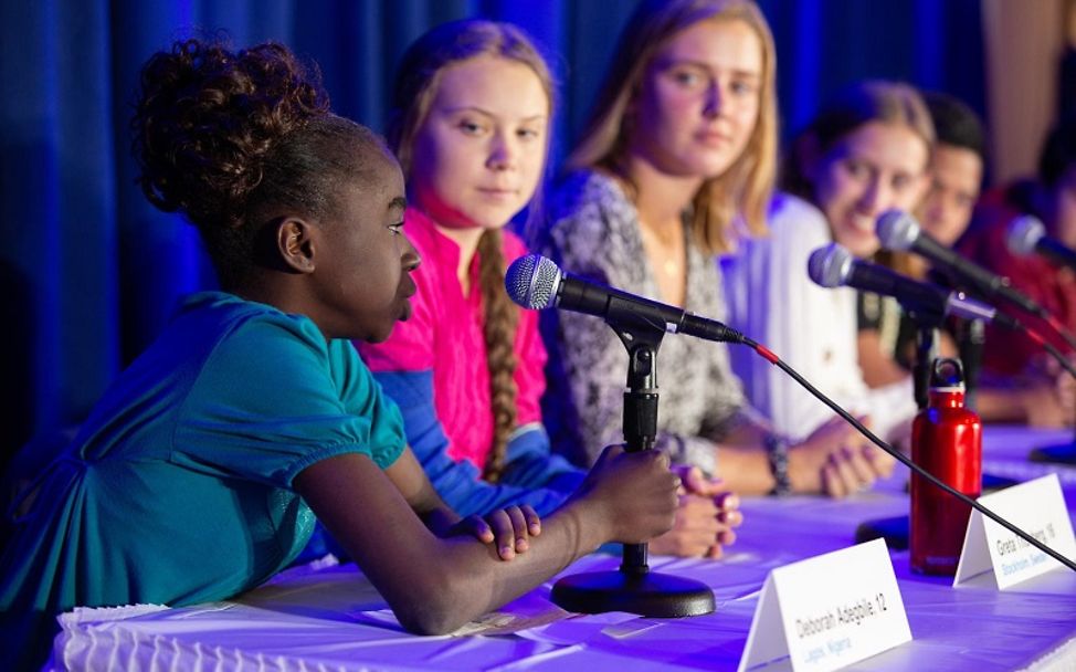 Morayo Adegbile aus Nigeria sitzt neben Greta Thunberg und anderen Jugendlichen auf dem Rednerpult.