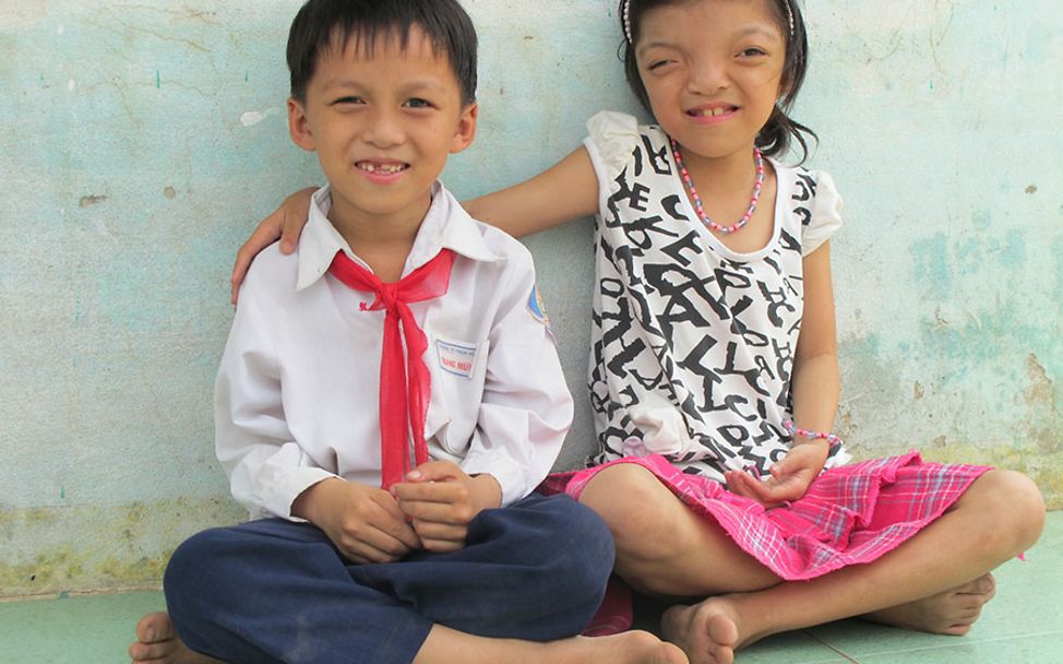 Vietnam: Ly und ihr Bruder Mung sitzen im Schneidersitz auf dem Boden.