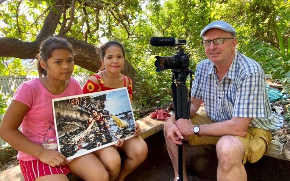 Philippinen: Hartmut Schwarzbach zeigt Wenie und ihrer Mutter das Siegerbild 2019.