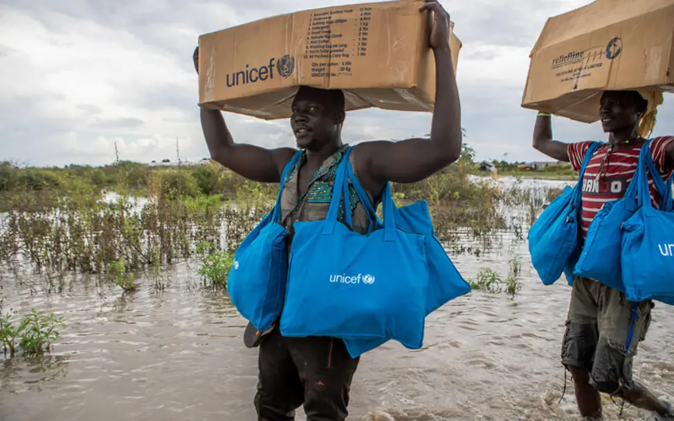 Südsudan: UNICEF-Mitarbeiter tragen Hilfsgüter durch überschwemmte Gebiete | © UNICEF/UNI224894/De La Guardia Südsudan: UNICEF-Mitarbeiter tragen Hilfsgüter durch überschwemmte Gebiete