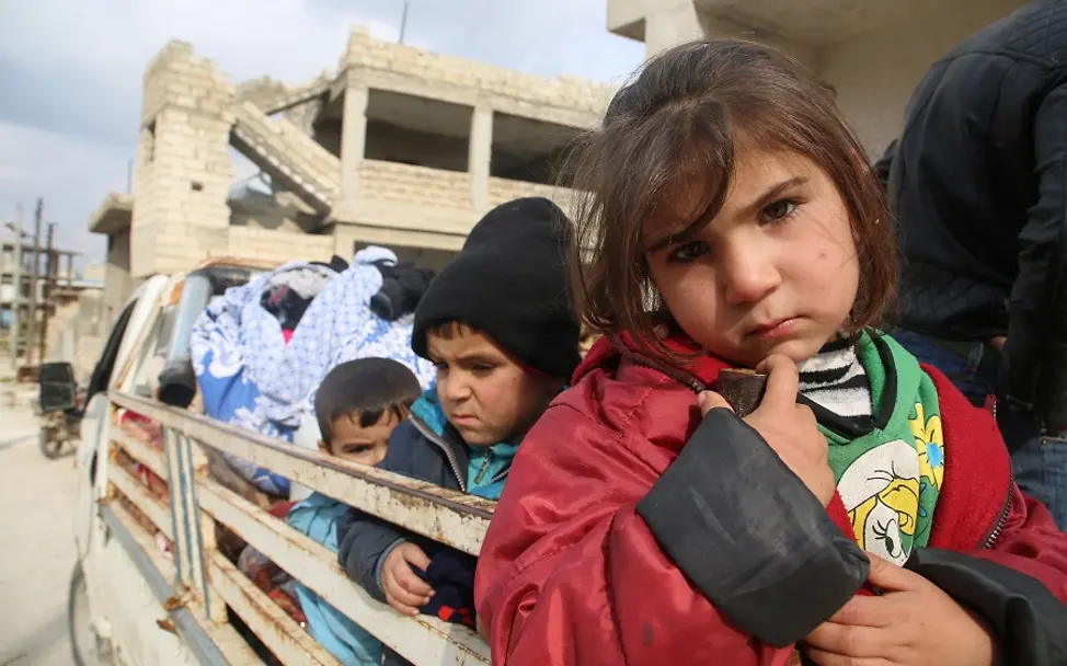 Auf der Flucht vor den eskalierenden Konflikten in Idlib/Syrien. | © UNICEF/Abdoullah Syrien: Kinder sitzen auf der Ladefläche eines Trucks, der durch eine zerstörte Stadt in Idlib fährt.