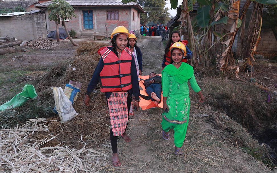 Nepal: Vier Kinder befördern einen Mann auf einer Trage.