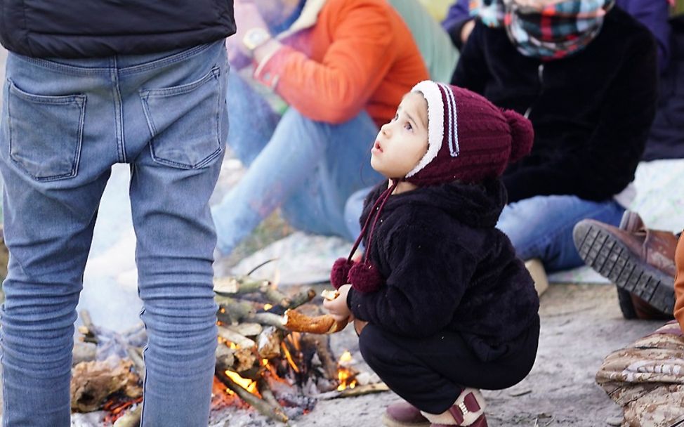 Türkei 2020: Ein Kleinkind hockt auf dem Boden vor einem Lagerfeuer. 