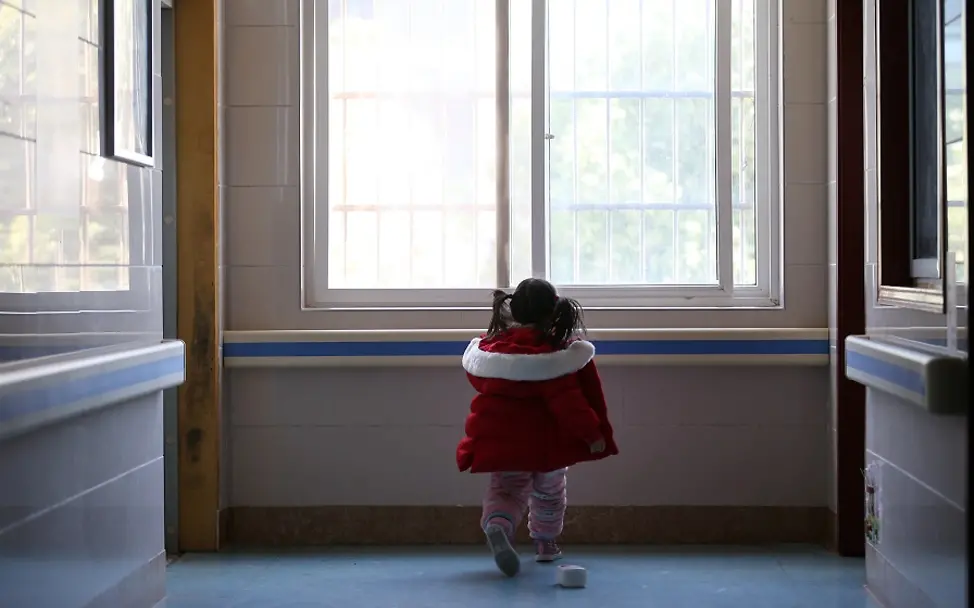 Ein Mädchen in einem Krankenhaus in Wuhan/China 2020. | © UNICEF/Cui Ein Mädchen steht vor einem Fenster in einem Krankenhausflur.