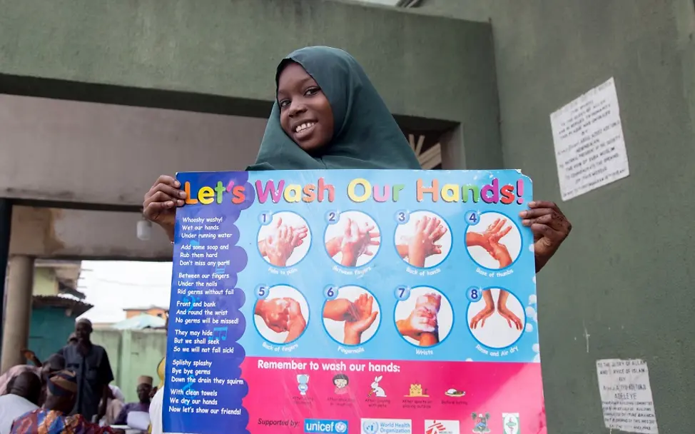 Nigeria 2020: Fardida Abdulazeez (9). | © UNICEF/Ojo Ein Mädchen hält ein Plakat zum Händewaschen und Prävention vor COVID-19 hoch.