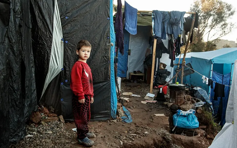 Ein Junge mit traurigem Blick in einem Flüchtlingslager. | © UNICEF/Romenzi Aufnahme griechischer Flüchtlingskinder in Deutschland: Ein Junge steht in einem Flüchtlingslager.