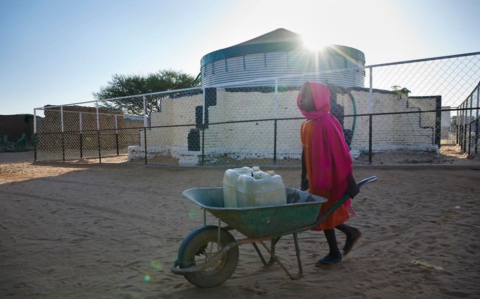 Sudan: Mädchen holt sich Trinkwasser mit Schubkarre.