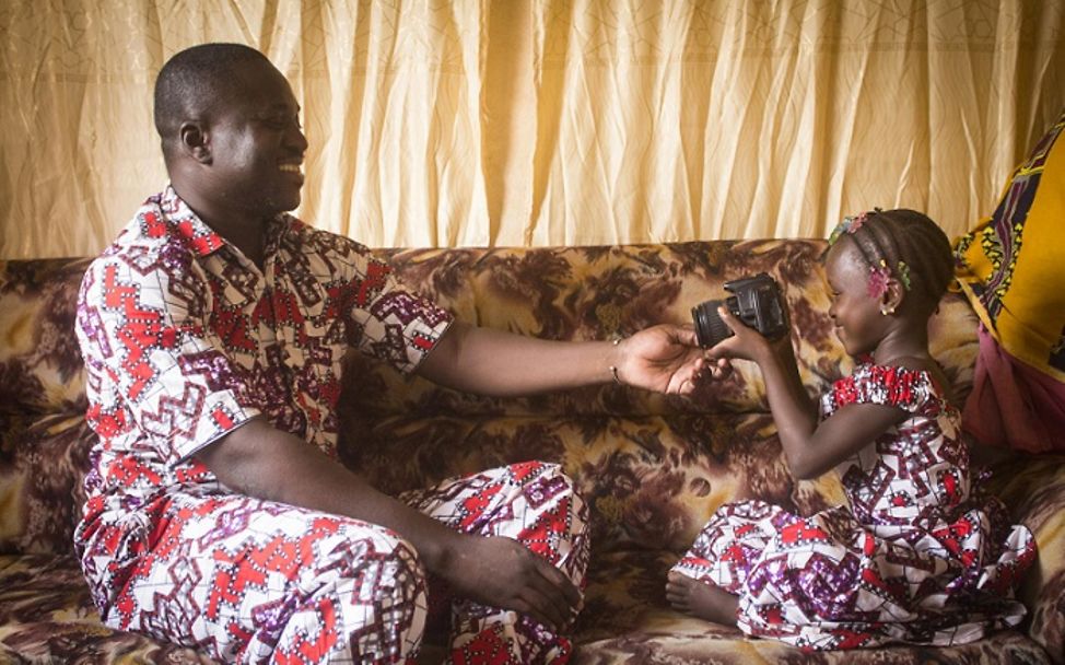 Mali: Tochter sitzt neben ihrem Vater auf der Couch.