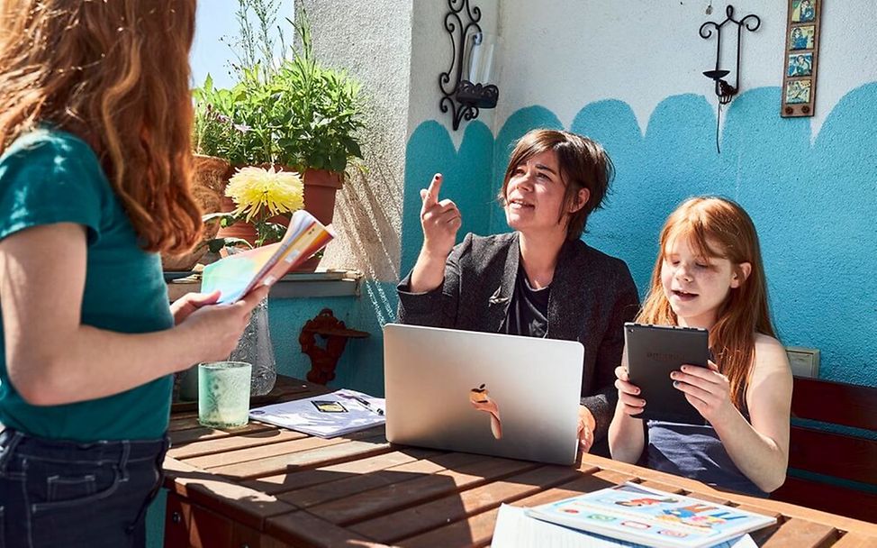 Kindererziehung: Eine Familie arbeitet auf dem Balkon.