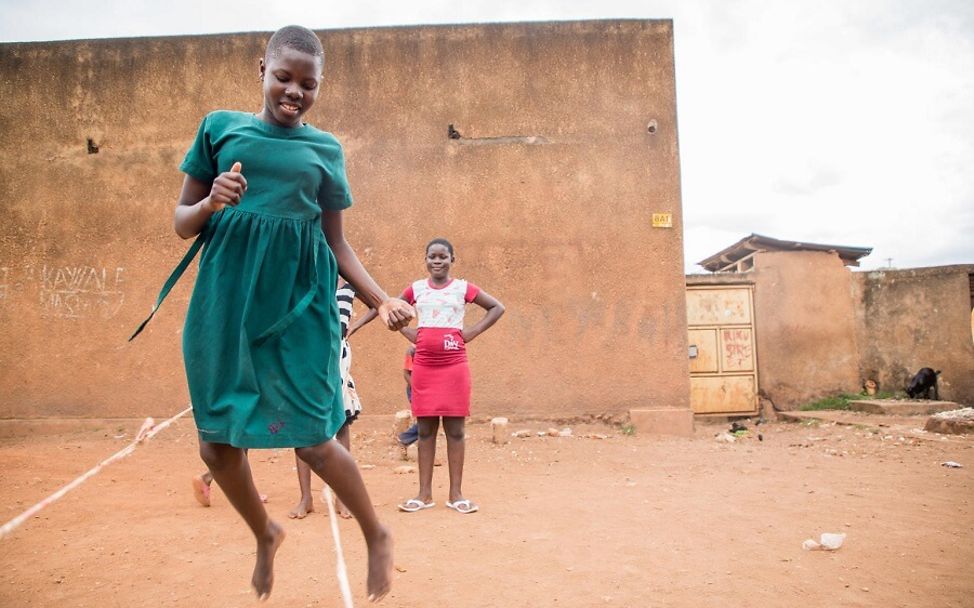 Corona Uganda: Mädchen spielen draußen Seilhüpfen.