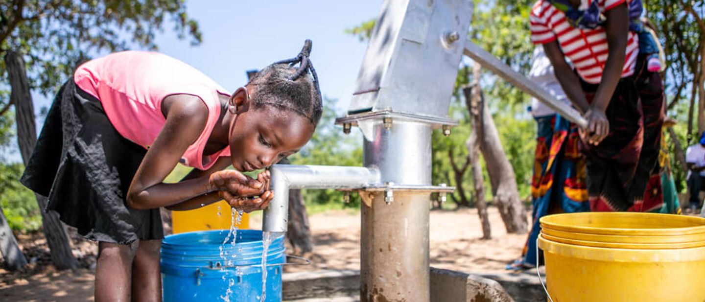 Dürre in Sambia 2020: Ein Mädchen trinkt Wasser aus einem Brunnen