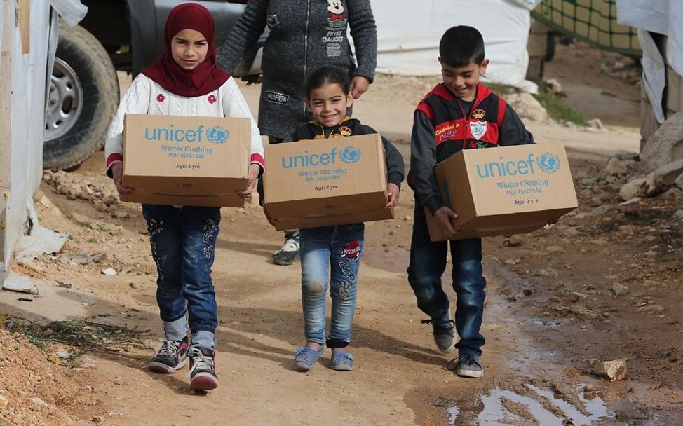 Nothilfe: Syrische Flüchtlingskinder tragen UNICEF-Hilfspakete.