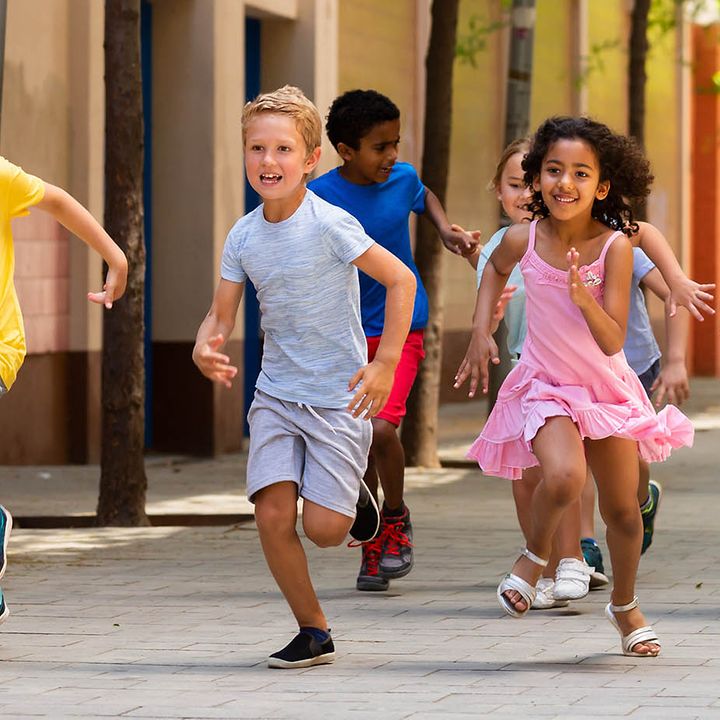 Eine Gruppe von Schulkindern läuft über den Pausenhof.