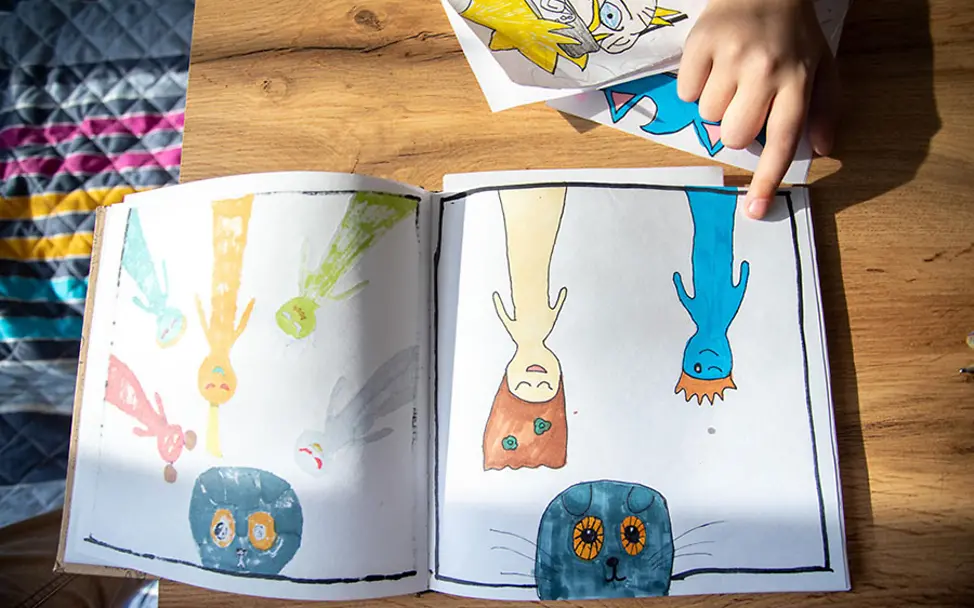 Masha zeigt ihre selbst gemalten Comics. | © UNICEF/Filippov Ukraine: Masha zeigt ihre selbst gemalten Comics.